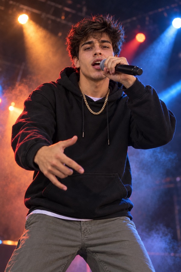 The same young man rapping into a microphone on stage