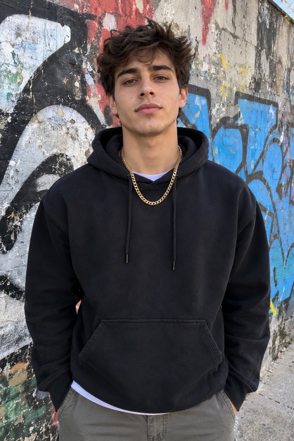 Selfie of a young man in a hoodie in front of a graffiti wall